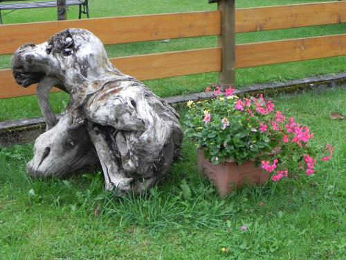 a statue of a dog sitting in the grass next to flowers at Ferienwohnung Schautzgy in Reutte