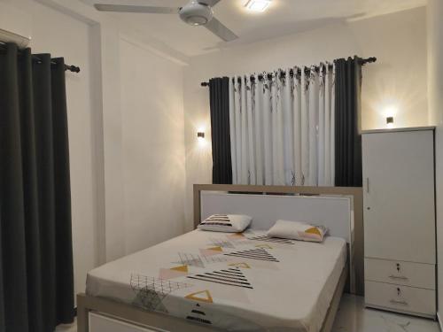 een slaapkamer met een bed met witte lakens en zwarte gordijnen bij Green Haven Villa in Hikkaduwa