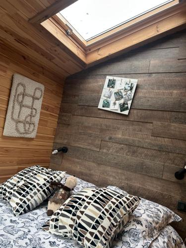ein Bett in einem Zimmer mit einer Holzwand in der Unterkunft Tiny House indépendante tout confort full équipement adult only-seulement in Morhange