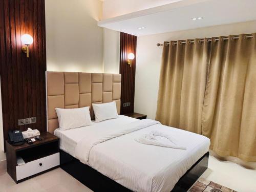 ein Schlafzimmer mit einem großen Bett mit weißer Bettwäsche in der Unterkunft Grand Khalifa Hotel Hamama in Sylhet