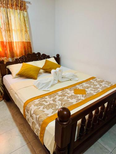 a bed with yellow and white blankets and pillows at The Travellers Rest in Katunayaka