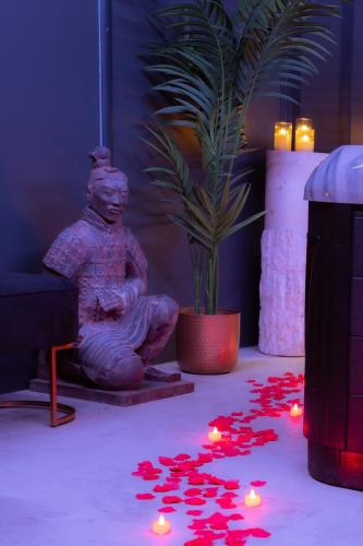 a statue sitting next to a potted plant with red lights at SuiteDreams - Ruby Suite Liège in Liège