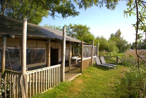 a house with a porch with a table and chairs at Glampingtent de Saskerlei, de Woudhaven in De Woude