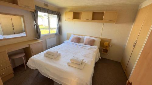 een kleine slaapkamer met een bed met handdoeken erop bij Suntrail House in Great Clacton