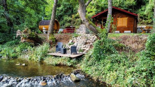 een houten brug over een rivier met een hut bij Eden Natural Resort - Transalpina in Căpîlna