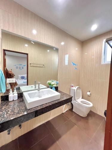 a bathroom with a sink and a toilet and a mirror at De' ozone ongsa pool villa หน้าหาดบางเสร่ in Bang Sare