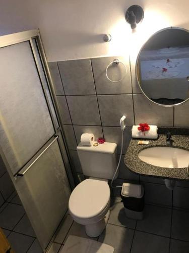 a bathroom with a toilet and a sink and a mirror at Pipa Hotel Pe na Areia in Pipa