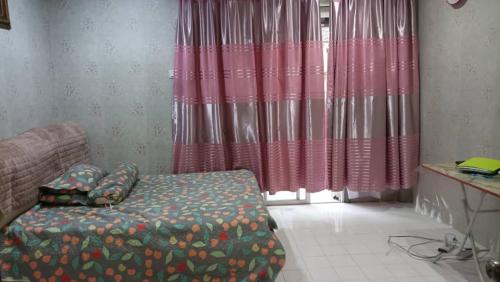 a living room with a bed and a window with curtains at el-yusra homestay in Bayan Lepas