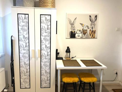 een tafel met twee krukjes naast een witte kast bij Lemuria Studio Łokietka in Legnica