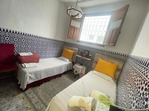 a small room with two beds and a window at Chez hiba in Rabat