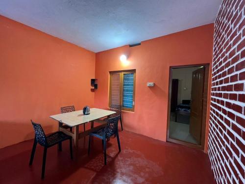 ein Esszimmer mit orangefarbenen Wänden sowie einem Tisch und Stühlen in der Unterkunft Wildlife stay in Kakkabe