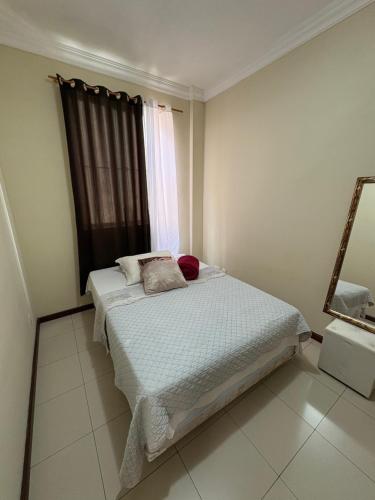 a bedroom with a bed with a window and a mirror at Quarto em apartamento in Ouro Preto