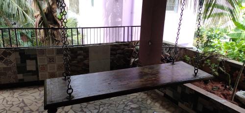 eine Holzbank, die an einen Balkon mit Fenster gekettet ist in der Unterkunft Block White Town Home Stay in Puducherry