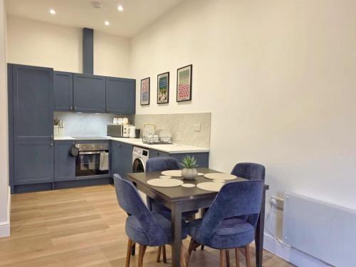 een keuken met een eettafel en blauwe stoelen bij Louisville Flat 4 in Newmarket