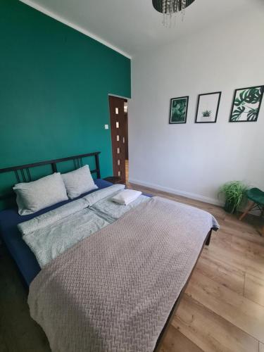 ein Schlafzimmer mit einem Bett und einer grünen Wand in der Unterkunft Apartament z widokiem Tarnowskie Góry in Tarnowitz