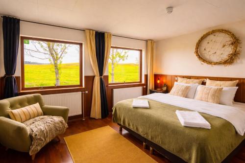 um quarto com uma cama grande e uma cadeira em Hotel Brú countryside em Selfoss
