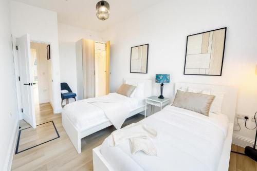 een witte kamer met 2 bedden en een stoel bij Louisville Flat 3 in Newmarket