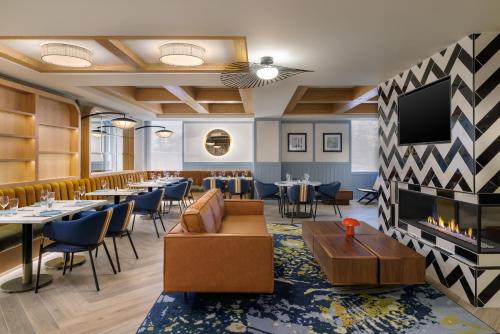 a restaurant with tables and chairs and a flat screen tv at EVEN Hotel Detroit North - Troy by IHG in Troy