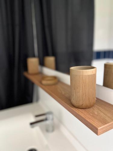 a brown cup sitting on a wooden shelf next to a sink at Charmante villa in Parentis-en-Born