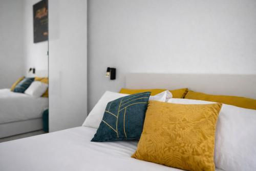 un letto con lenzuola bianche e un cuscino giallo di Maison Chanel a Milano