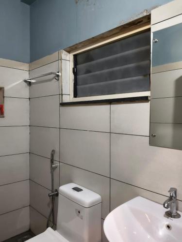 a bathroom with a toilet and a sink and a window at Hotel Riviera in Mananthavady