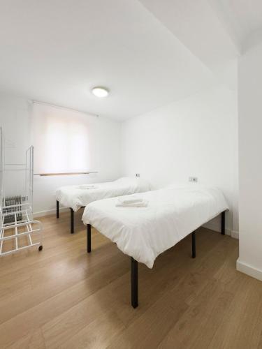 two beds in a room with a white wall at Apartamento Nayara in Alcañiz
