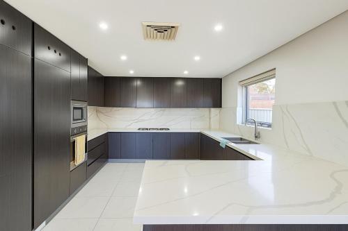 a kitchen with dark wood cabinets and a sink at Fascinating Neon - Master Room Beside Station - With Private bathroom and walk-in wardrobe in Sydney