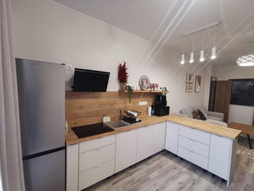 een keuken met witte kasten en een roestvrijstalen koelkast bij River Apartman 1 in Odorheiu Secuiesc