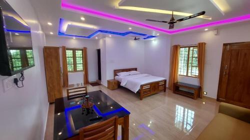 a bedroom with a bed and a kitchen with purple lights at Carmel Building in Marayoor