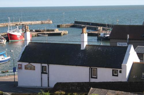 a small white building with a boat in the water at Gowan Bank in Gourdon