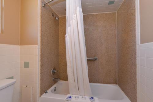 a shower with a white shower curtain in a bathroom at Ranch House Motel in Sweetwater