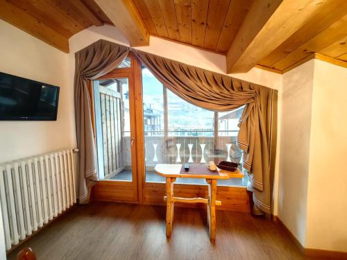 einen kleinen Tisch in einem Zimmer mit einem großen Fenster in der Unterkunft Hotel Ambassador Bormio in Bormio