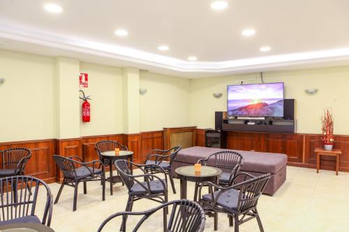 a waiting room with tables and chairs and a flat screen tv at Insitu Eurotel Andorra in Andorra la Vella