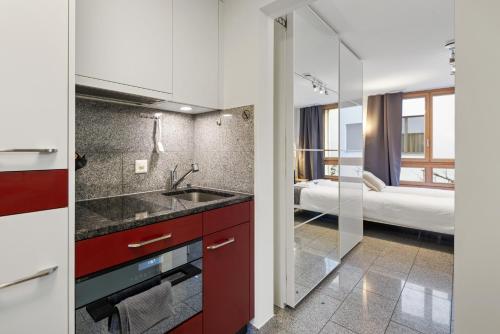 Una cocina con fregadero y un baño con cama. en Bergstudio II I Flims I Laax I Ski I Caumasee, en Flims