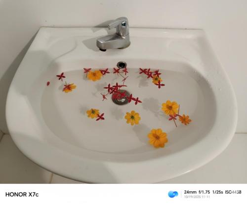 een wit toilet met bloemen in de wastafel bij Almond Breeze Cottage in Udawalawe