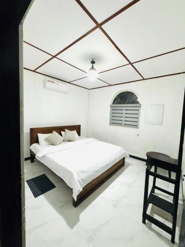 a white bedroom with a bed and a chair at Seliya Villa Retreat in Balapitiya