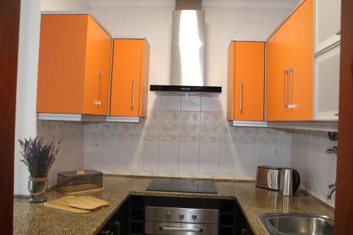 eine Küche mit orangefarbenen Schränken und einem Waschbecken in der Unterkunft Alojamento Bem-me-quer in Reguengos de Monsaraz
