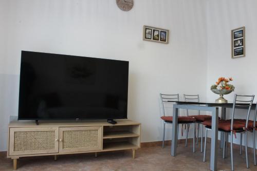 einen Flachbild-TV auf einem Stand mit einem Tisch in der Unterkunft Alojamento Bem-me-quer in Reguengos de Monsaraz