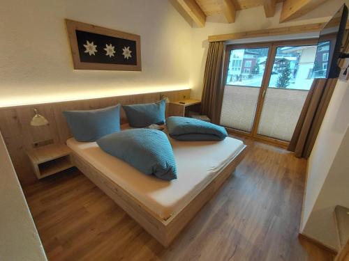 a bedroom with a bed with blue pillows and a window at Apart Monte Vista in Längenfeld