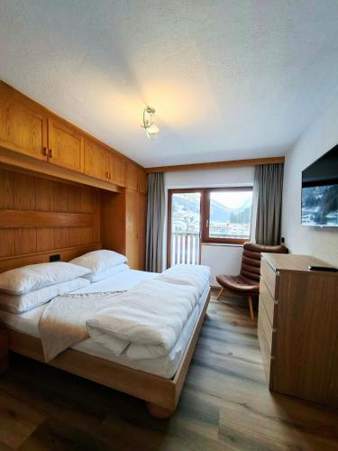 ein Schlafzimmer mit einem großen Bett und einem Fernseher in der Unterkunft Hamatli Paznaun in Kappl