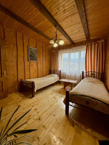 a bedroom with two beds in a room with wooden walls at Гуцульська оселя in Yaremche