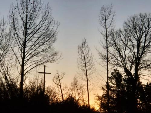 a cross in the middle of some trees at sunset at Hermosa Cabaña en medio de la naturaleza in Los Angeles