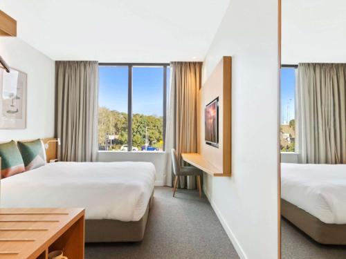 Una habitación de hotel con dos camas y un escritorio. en Mantra on Sydney Airport, en Sídney
