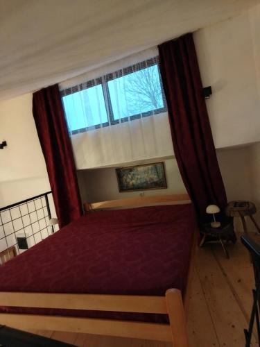 a bedroom with a red bed and a window at Apartman "Galerija" in Pirot