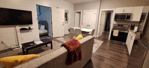 a living room with a couch and a kitchen at Two Bedroom Suite with AC, Sleeps 8- Welcome Snacks and Drinks Included in Langford
