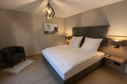 a bedroom with a white bed and a chair at Bergflamme - Ihr Ferienhaus im Harz mit Panoramasauna in Braunlage