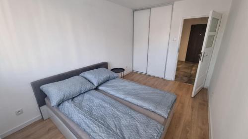 ein Schlafzimmer mit einem Bett mit einer blauen Decke in der Unterkunft Sadyba Apartament in Nowy Sącz