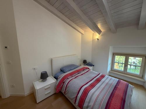 a white bedroom with a bed and a window at La Piccola Perla di Rovereto in Rovereto