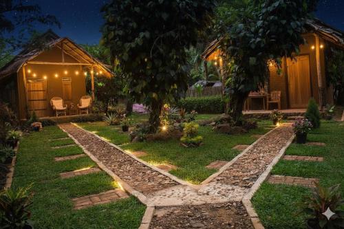 een tuin 's nachts met een huis met verlichting bij Almond Breeze Cottage in Udawalawe