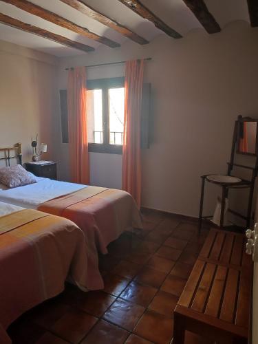 a bedroom with two beds and a window and a chair at Alojamiento Rural Tres Palacios in Molina de Aragón